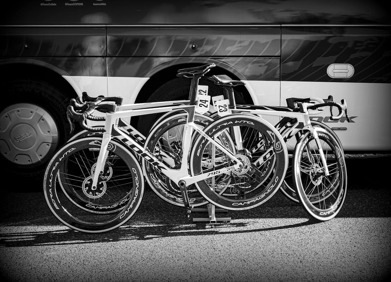 Monochrome photo of racing bicycles parked in front of a bus in a sports event setting.